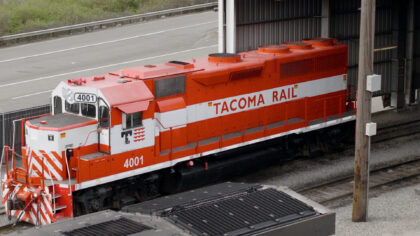 An red and white locomotive labeled "4001" from Tacoma Rail is parked under a shelter, showing its distinct front design and side lettering.